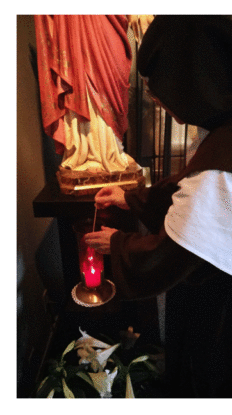Sister lights a devotional candle with Paschal Flame